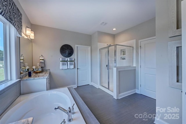 bathroom with a garden tub, wood finished floors, visible vents, vanity, and a stall shower