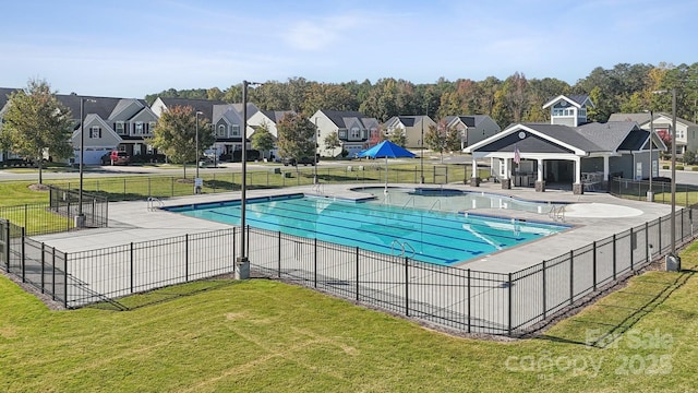 community pool featuring a residential view, fence, a lawn, and a patio