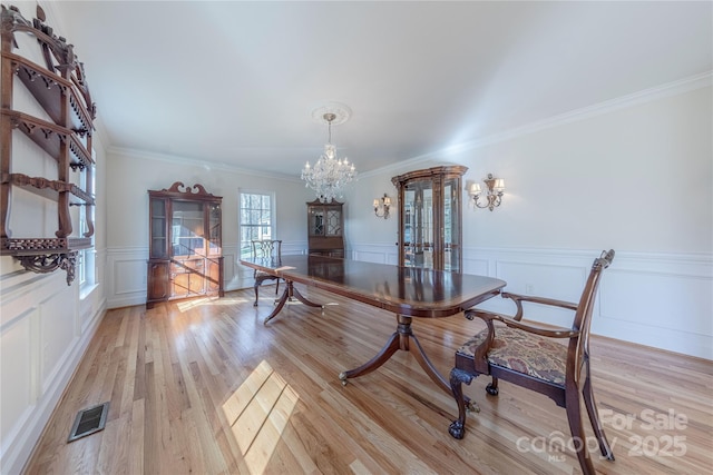 dining area with crown molding, a chandelier, and light wood-type flooring