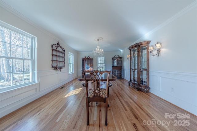 dining room with light hardwood / wood-style flooring, ornamental molding, and an inviting chandelier