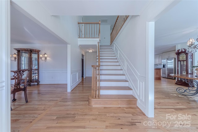 staircase featuring wood-type flooring, an inviting chandelier, and crown molding