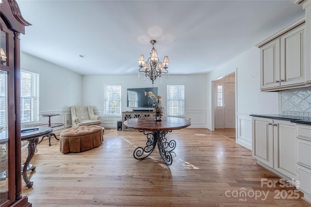 dining space featuring light wood-type flooring, plenty of natural light, and an inviting chandelier