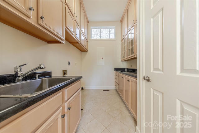 kitchen featuring light tile patterned floors, light brown cabinets, and sink