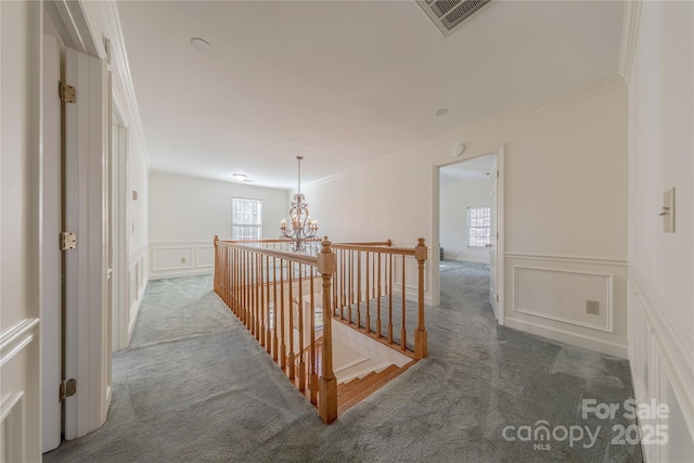 hall featuring a chandelier, crown molding, and dark carpet