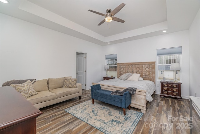 bedroom with a raised ceiling, wood finished floors, and baseboards