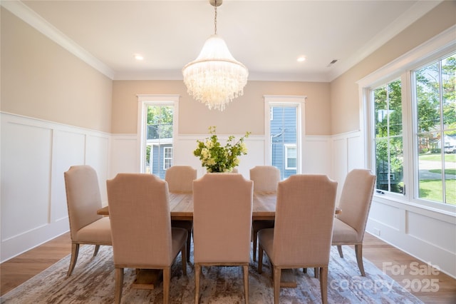 dining room with hardwood / wood-style flooring, ornamental molding, and a chandelier