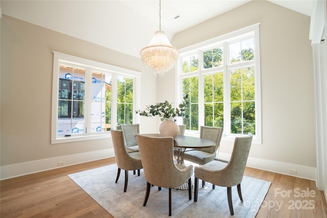 dining space featuring a healthy amount of sunlight, light wood-type flooring, and a chandelier