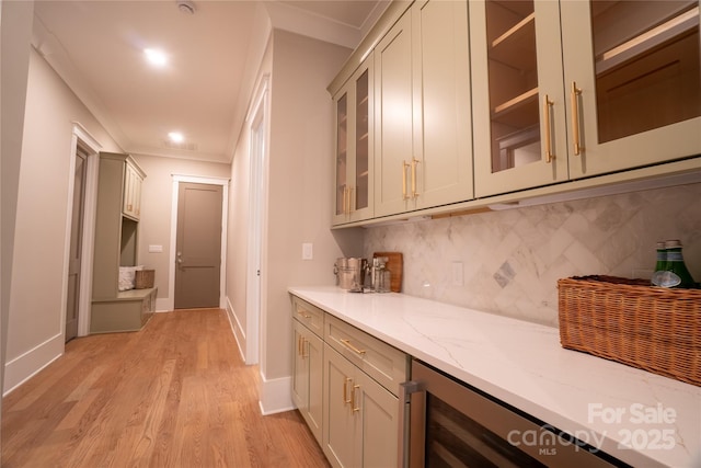 bar with decorative backsplash, crown molding, light hardwood / wood-style flooring, and light stone counters