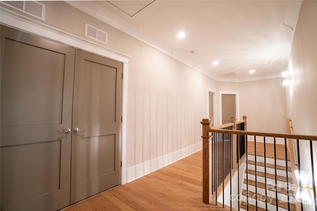 corridor with light wood-type flooring and crown molding