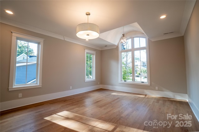 spare room featuring a notable chandelier, crown molding, and hardwood / wood-style flooring