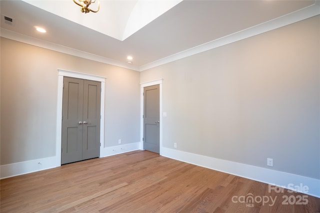 unfurnished bedroom featuring a closet, crown molding, and light wood-type flooring