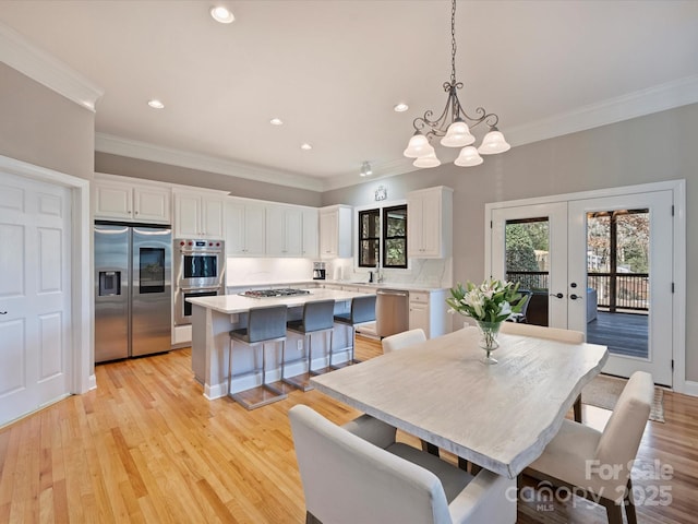 dining room featuring recessed lighting, light wood-style flooring, crown molding, and french doors