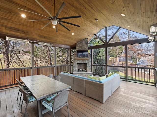 sunroom featuring wood ceiling, an outdoor stone fireplace, a ceiling fan, and lofted ceiling