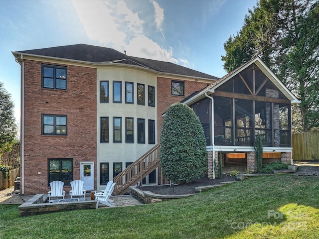 rear view of house with a fire pit, a patio, a sunroom, stairs, and a yard