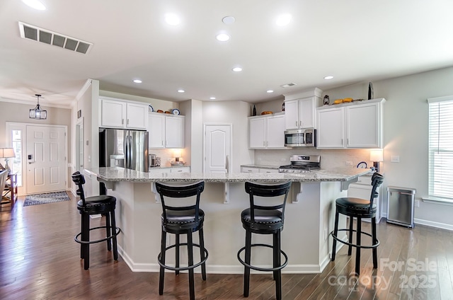 kitchen featuring a kitchen bar, a large island with sink, white cabinets, and stainless steel appliances