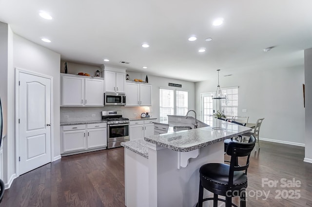 kitchen featuring pendant lighting, sink, white cabinetry, an island with sink, and stainless steel appliances