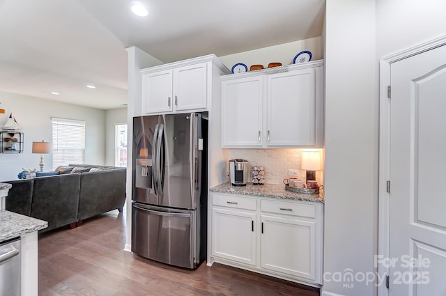 kitchen with light stone countertops, tasteful backsplash, white cabinetry, dark wood-type flooring, and stainless steel appliances