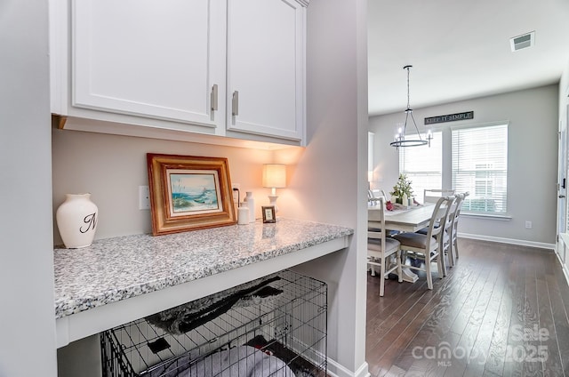 kitchen featuring decorative light fixtures, white cabinets, and light stone counters