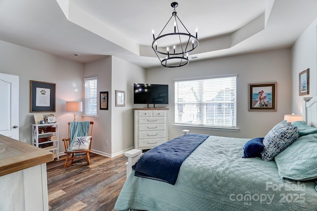 bedroom with a raised ceiling, an inviting chandelier, and dark wood-type flooring