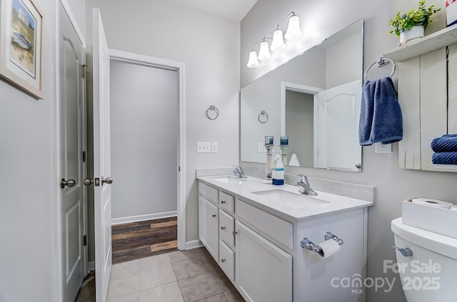 bathroom with toilet, vanity, and tile patterned flooring