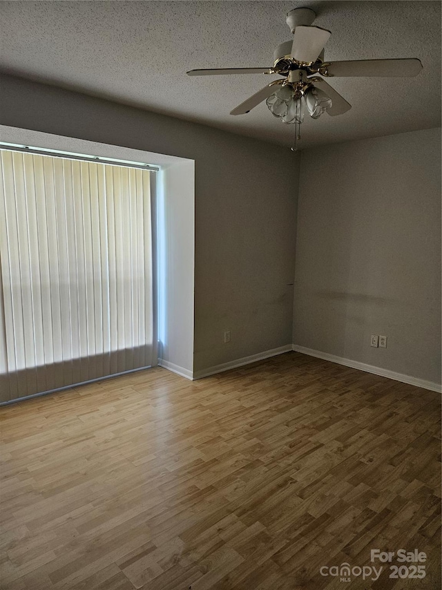 unfurnished room with a textured ceiling, baseboards, and wood finished floors