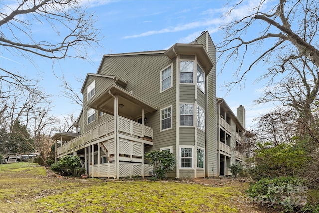 back of house with a balcony and a yard