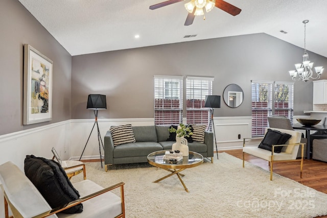 living room featuring ceiling fan with notable chandelier, light hardwood / wood-style flooring, and vaulted ceiling