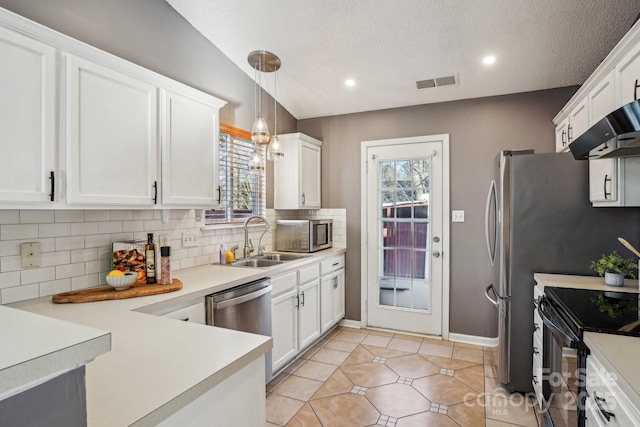 kitchen with pendant lighting, vaulted ceiling, sink, white cabinets, and stainless steel appliances