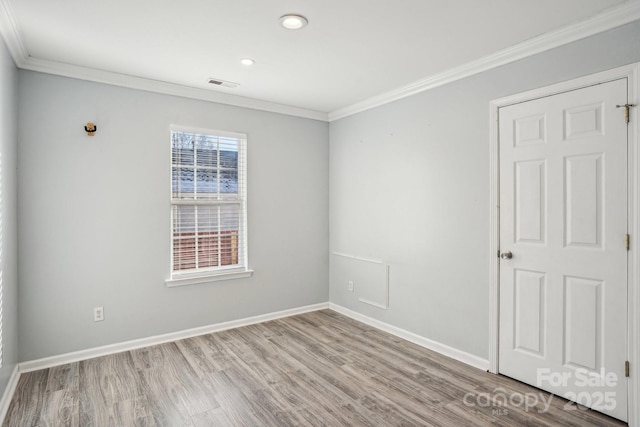 empty room featuring crown molding and light wood-type flooring