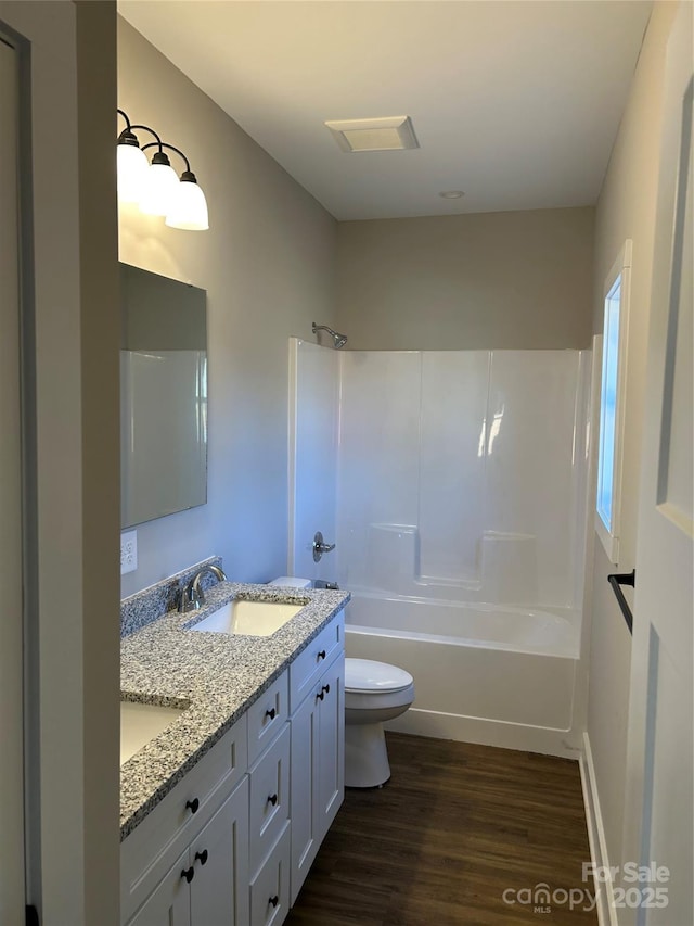 full bathroom with toilet, hardwood / wood-style flooring, vanity, and washtub / shower combination