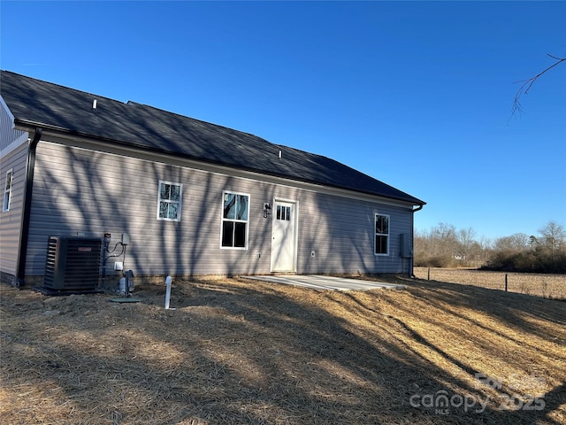 back of property featuring central AC unit, a patio area, and a lawn