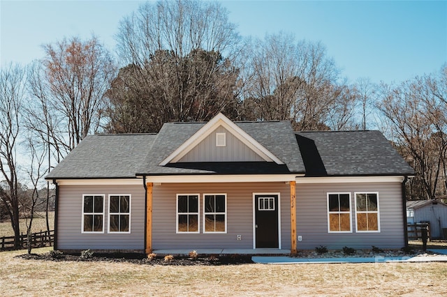 view of front of property with a shingled roof, board and batten siding, and fence