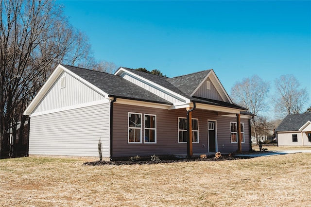 view of front of house with roof with shingles, a front lawn, and board and batten siding