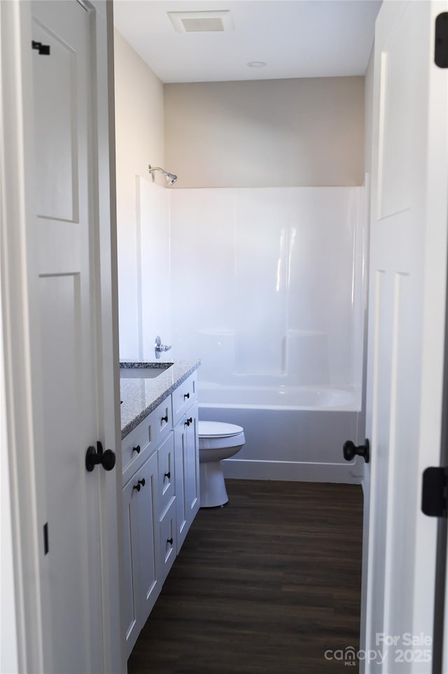 full bath featuring shower / bath combination, visible vents, toilet, wood finished floors, and vanity