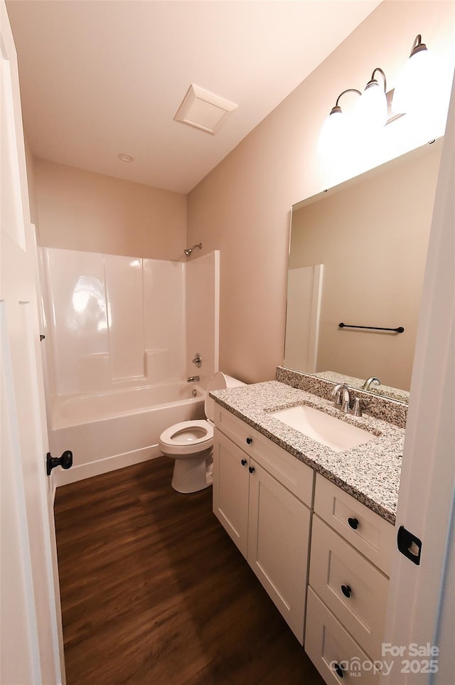 bathroom featuring toilet, vanity, shower / tub combination, and wood finished floors