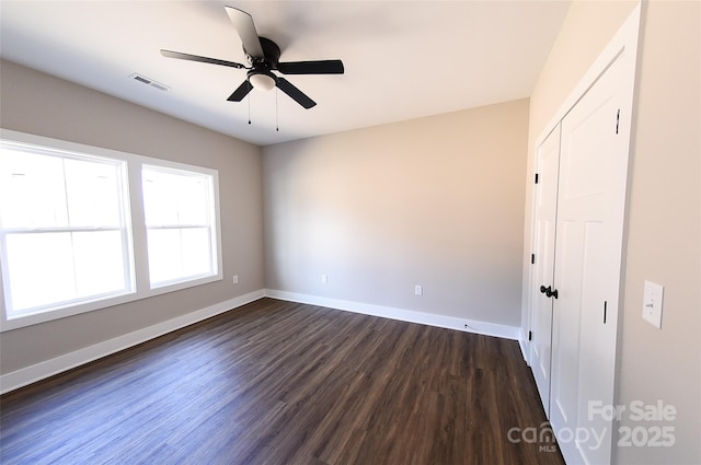 interior space with baseboards, a closet, visible vents, and dark wood-type flooring