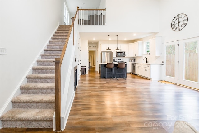 stairs with hardwood / wood-style flooring, sink, and a towering ceiling