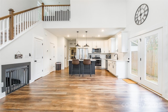 kitchen with white cabinetry, stainless steel appliances, backsplash, hanging light fixtures, and a kitchen island