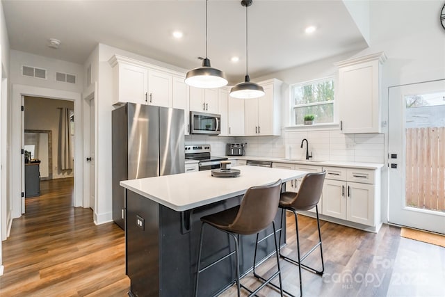 kitchen featuring pendant lighting, white cabinets, a center island, and stainless steel appliances