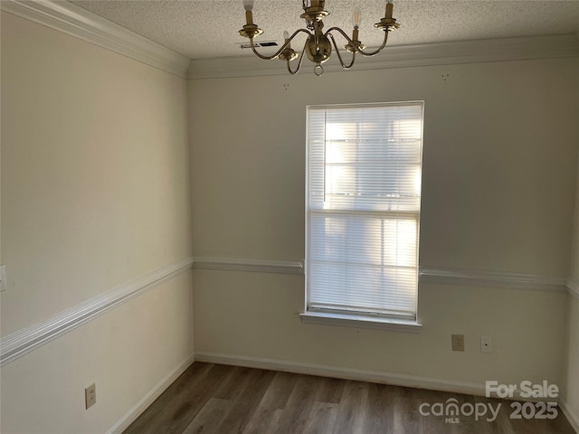 spare room featuring ornamental molding, dark hardwood / wood-style floors, a chandelier, and a textured ceiling