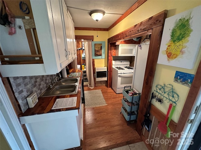 kitchen with sink, heating unit, gas range gas stove, white cabinetry, and decorative backsplash