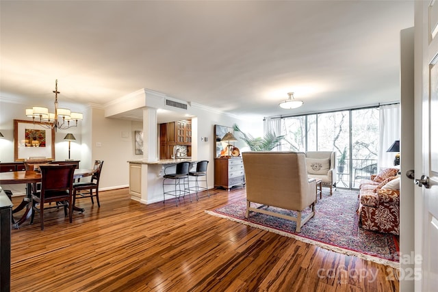 living room with crown molding, expansive windows, a chandelier, and light hardwood / wood-style flooring