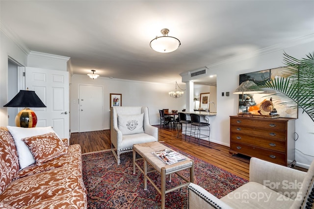 living room featuring crown molding, dark hardwood / wood-style flooring, and an inviting chandelier