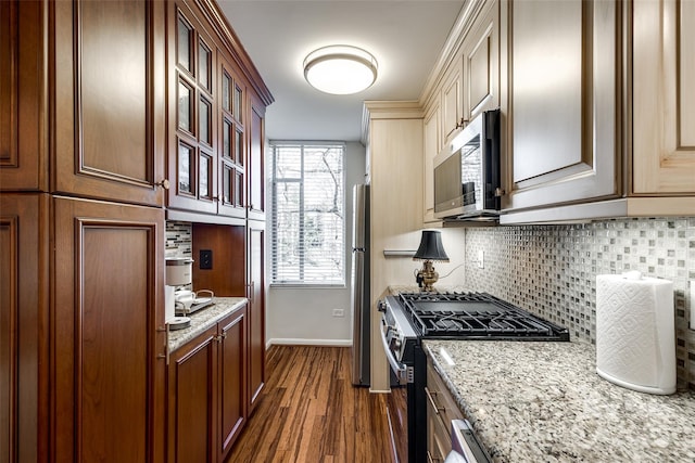 kitchen featuring stainless steel appliances, light stone countertops, dark hardwood / wood-style floors, and backsplash