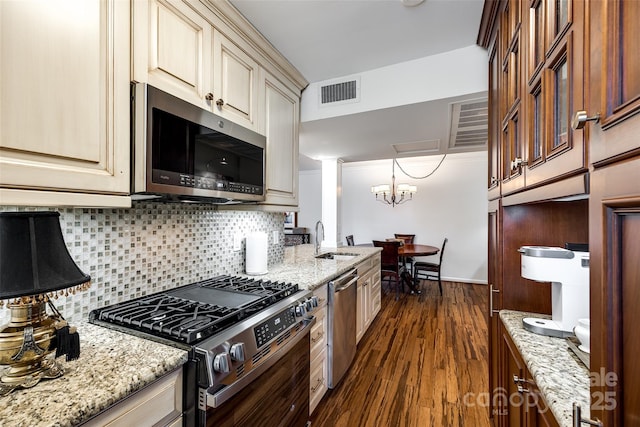 kitchen with light stone countertops, appliances with stainless steel finishes, sink, and cream cabinetry