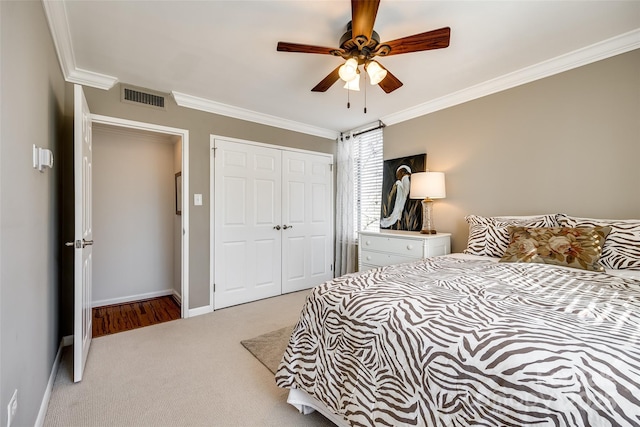 carpeted bedroom with crown molding, ceiling fan, and a closet