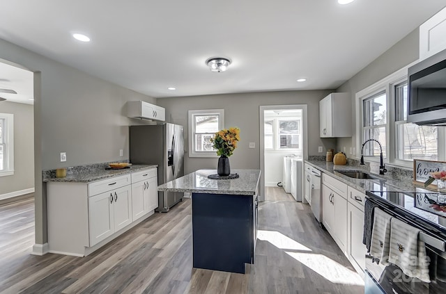 kitchen with white cabinets, a center island, stainless steel appliances, sink, and independent washer and dryer