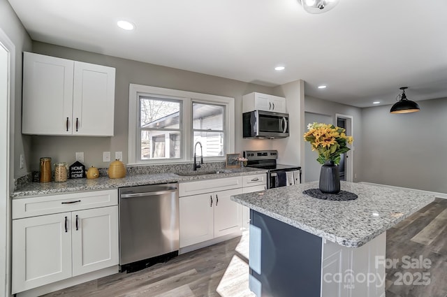 kitchen with light hardwood / wood-style floors, stainless steel appliances, a kitchen island, white cabinets, and sink