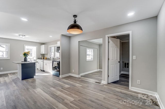 kitchen with decorative light fixtures, a wealth of natural light, white cabinets, and appliances with stainless steel finishes