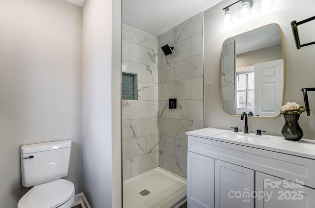 bathroom featuring tiled shower, vanity, and toilet